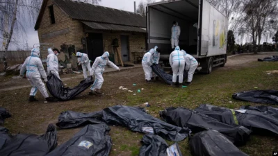 Волонтери завантажують тіла мирних жителів, убитих у Бучі, у вантажівку, щоб відвезти їх до моргу для розслідування, Україна, 12 квітня 2022 року.