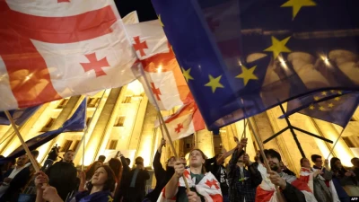 Протестувальники несуть прапори Грузії та Євросоюзу під час протесту біля парламенту проти законопроекту про 