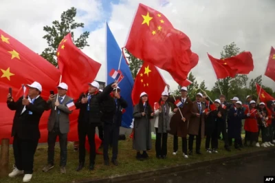 Люди з китайськими прапорами вітають президента Китаю Сі Цзіньпіна в селі Баньєр-де-Бігор поблизу гірськолижного курорту Ла-Монжі, 7 травня 2024.