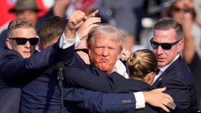 Колишній президент США від Республіканської партії Дональд Трамп махає кулаком, коли агенти допомагають йому зійти зі сцени під час передвиборчого мітингу в Батлері, штат Пенсільванія, у суботу, 13 липня 2024 р. (AP Photo/Gene J. Puskar)