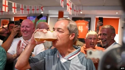 Найджел Фарадж у футболці збірної Англії 1996 року п’є пиво з англійськими футбольними уболівальниками під час трансляції футбольного матчу Євро-2024, північно-західна Англія, 20 червня 2024 р. Oli SCARFF/AFP